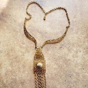 Vintage necklace with several ornate pieces hanging from a gold tone chain.
